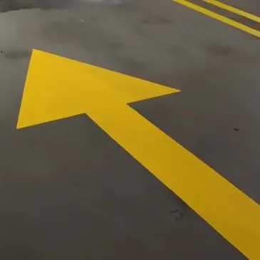 Yellow directional arrows painted on asphalt road